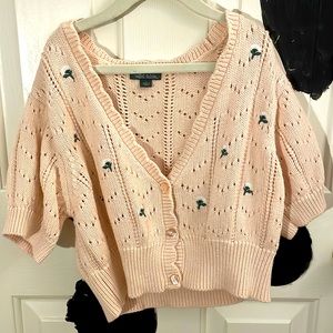 Pink knitted kind of look sweater with flowers on it